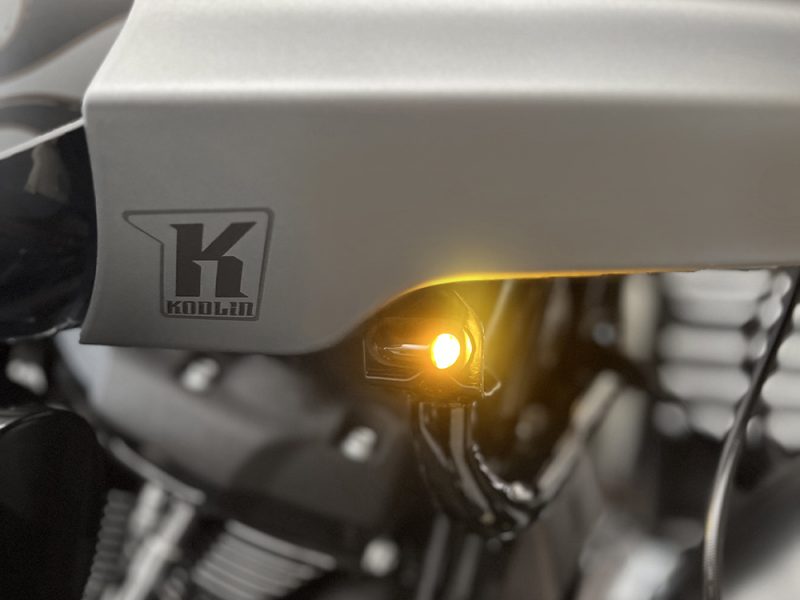Koolan motorcycle logo and yellow indicator light on motorcycle engine.
