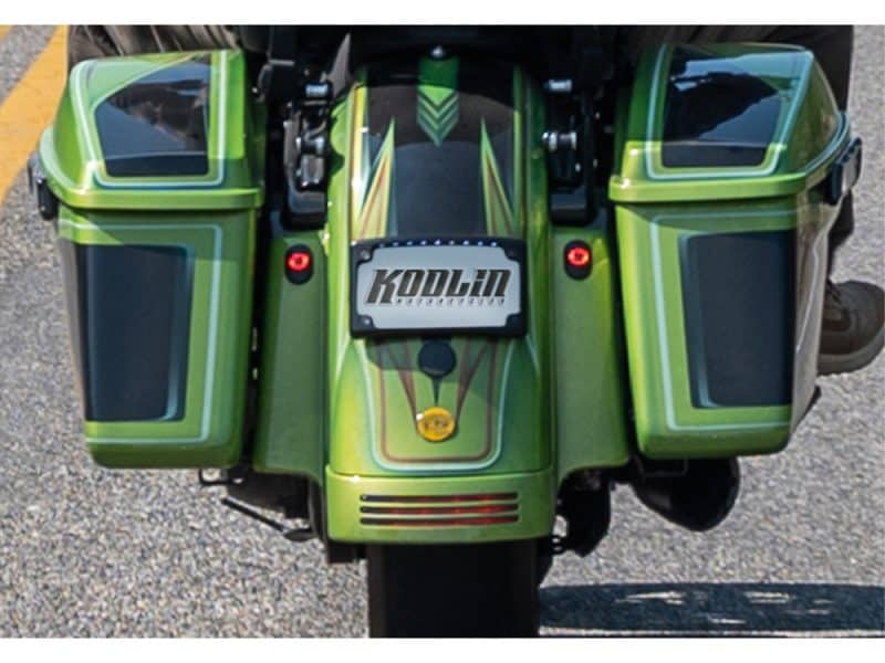 Vibrant green motorcycle with custom KoDin motoracing branding and storage compartments for touring.