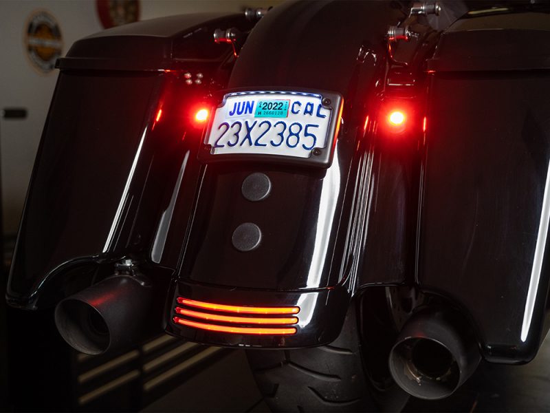 Shiny black cruiser motorcycle with illuminated rear lights and Australian license plate.
