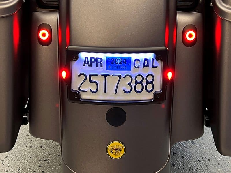 License plate with illuminated characters on a motorcycle, showing registration details and LED lights.