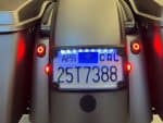 Custom motorcycle license plate with LED lights and rear tail light, parked on Revelry Motorcycles.