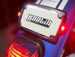 Koulou Motorcycles logo displayed on a motorcycle LED screen with vibrant red taillight illumination.