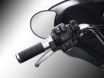Motorcycle handlebar controls and rear-view mirror on a black motorcycle.