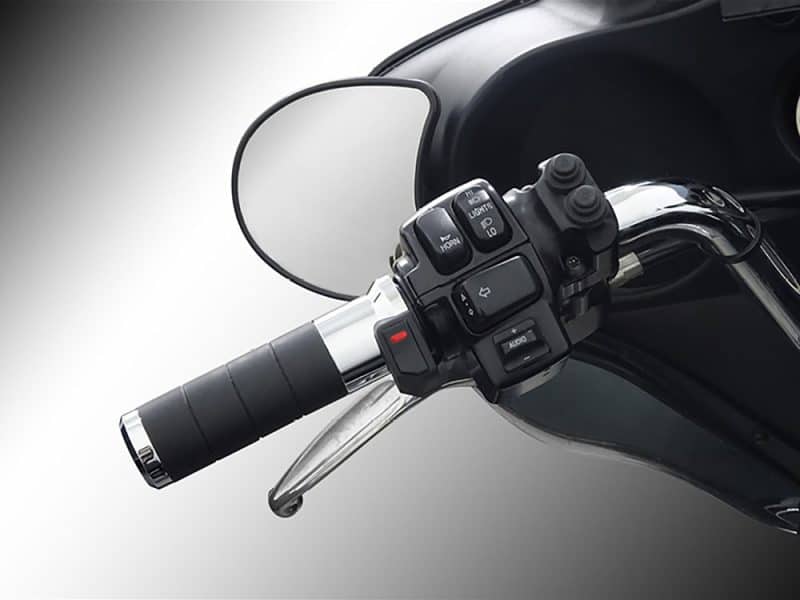 Motorcycle handlebar controls and rear-view mirror on a black motorcycle.