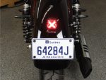 Vintage Quebec motorcycle license plate with tail light and suspension details.