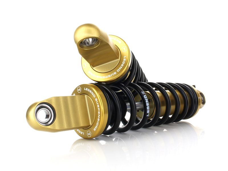 High-performance motorcycle suspension shocks with gold accents for off-road and street riding.