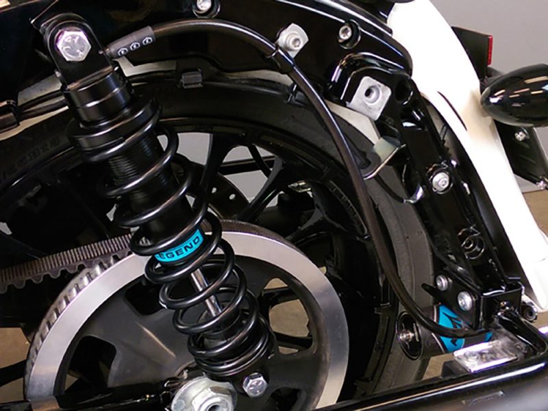 Robust motorcycle rear suspension and belt drive system at Revelry Motorcycles, stylish black and silver components.