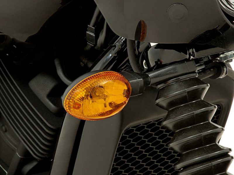 Motorcycle front turn signal and radiator grille close-up photo.