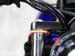 Chrome plate motorcycle fork with illuminated indicator light, close-up detail.