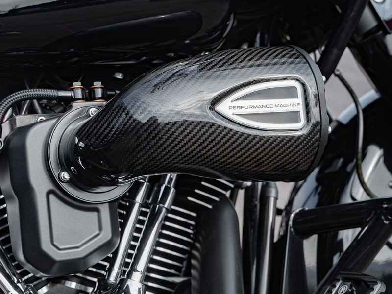 High-performance motorcycle air filter with carbon fibre finish and "Performance Machine" branding.