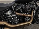 V-Twin motorcycle engine with custom exhaust pipes and performance air filter, sleek black and bronze design.