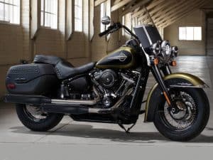 Harley-Davidson touring motorcycle with leather saddle bags inside a spacious wooden warehouse.