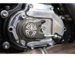 Black motorcycle engine close-up with spider logo, highlighting custom parts and mechanical detail.
