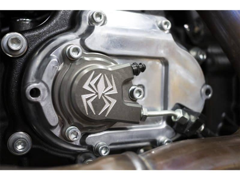 Black motorcycle engine close-up with spider logo, highlighting custom parts and mechanical detail.