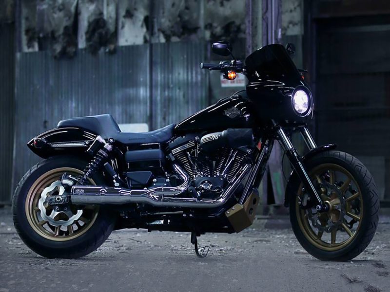 Harley Davidson black motorcycle with gold wheels in an industrial setting.