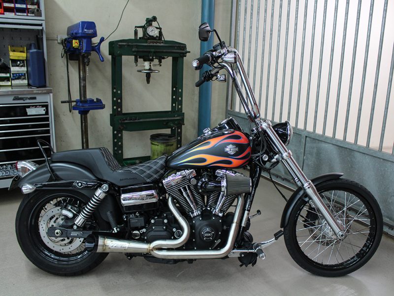 Harley-Davidson motorcycle with flame paint job in workshop setting.