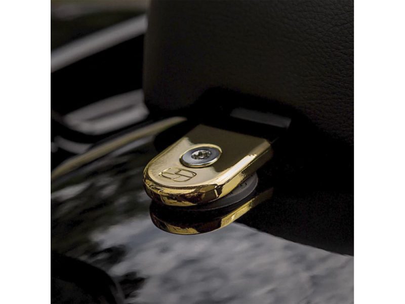 Shiny gold motorcycle seat lock with Harley-Davidson logo detail in close-up.