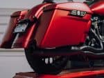 Shiny red motorcycle with custom side storage and skull emblem details.