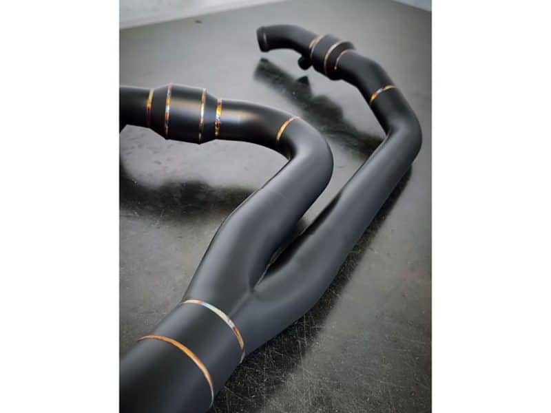 Sleek black motorcycle exhaust pipes with gold accents, ideal for custom motorbikes and enhancing performance.