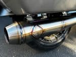Shiny motorcycle exhaust pipe with colourful welds at Revelry Cycles, promoting high-performance motorcycle accessories.