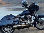 Harley-Davidson touring motorcycle with custom exhaust bike parked near water Recreational motorcycle, black and chrome, ideal for road trips and touring enthusiasts.