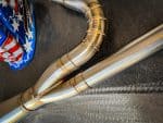 High-performance motorcycle exhaust system with polished metal finish for Revelry Motorcycles.