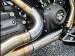 Chromed motorcycle exhaust pipes with Harley Davidson engine details.