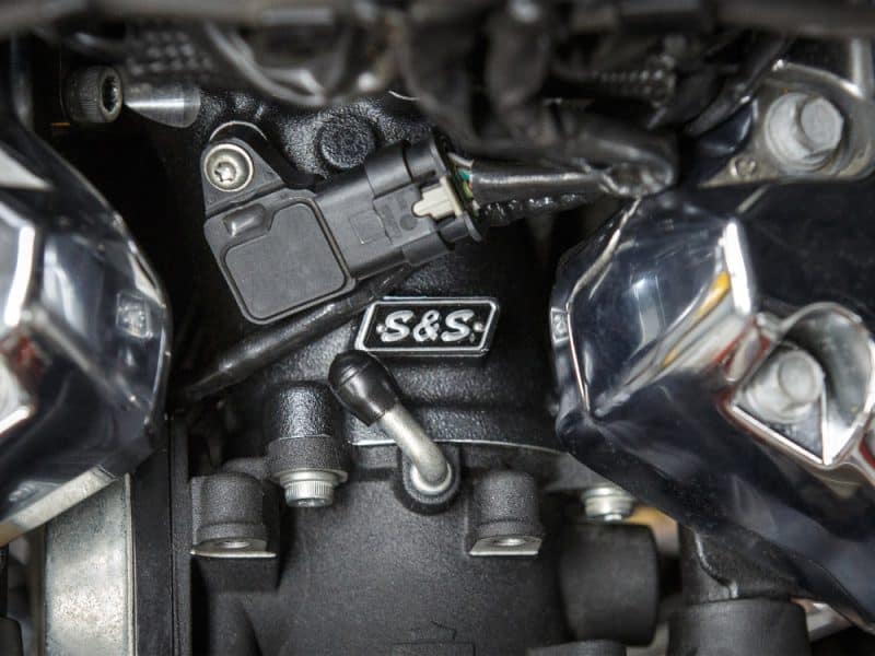 Engine close-up with S&S badge on a motorcycle, showcasing mechanical components and high-performance parts.