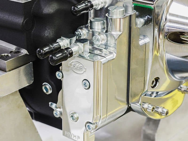 Precision motorcycle engine component with chrome finish and mechanical fittings.