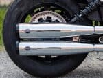 Dual S&S exhaust pipes on a black motorcycle rear wheel, showcasing performance exhaust system.