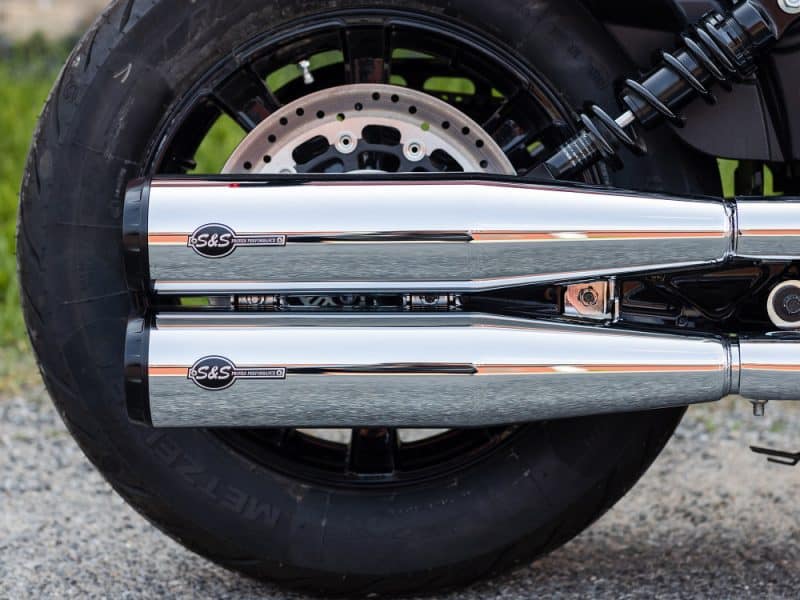 Dual S&S exhaust pipes on a black motorcycle rear wheel, showcasing performance exhaust system.