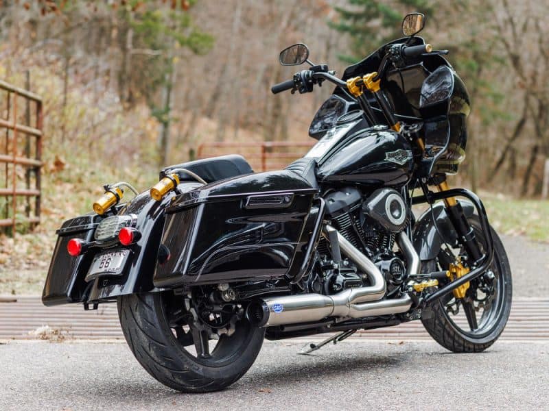 Dark custom motorcycle with black paint and sleek design in an outdoor setting.
