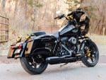 Vivid black custom Harley-Davidson motorcycle with gold accents on a scenic outdoor road.
