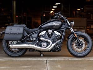 Vivid black Indian motorcycle with leather saddlebag on a warehouse background.
