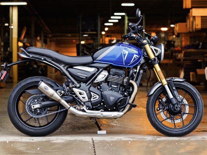 4in. Grand National Slip-On Muffler - Stainless Steel with Black End Cap. Fits Triumph Speed 400 & Scrambler 400X 2024up Vibrant blue Triumph motorcycle displayed in a workshop setting, showcasing high-performance design and craftsmanship.