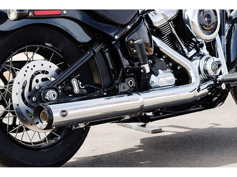 Vented disc brake and chrome exhaust pipe on a Harley-Davidson motorcycle in black and silver.
