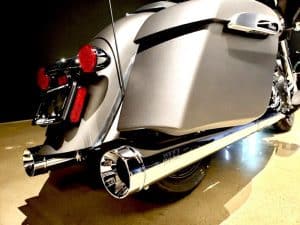 Sleek grey touring motorcycle with chrome dual exhaust pipes and side storage panniers.