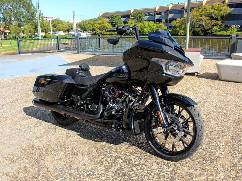 Black touring motorcycle parked at a waterfront park in Australia, perfect for custom rides and adventure.