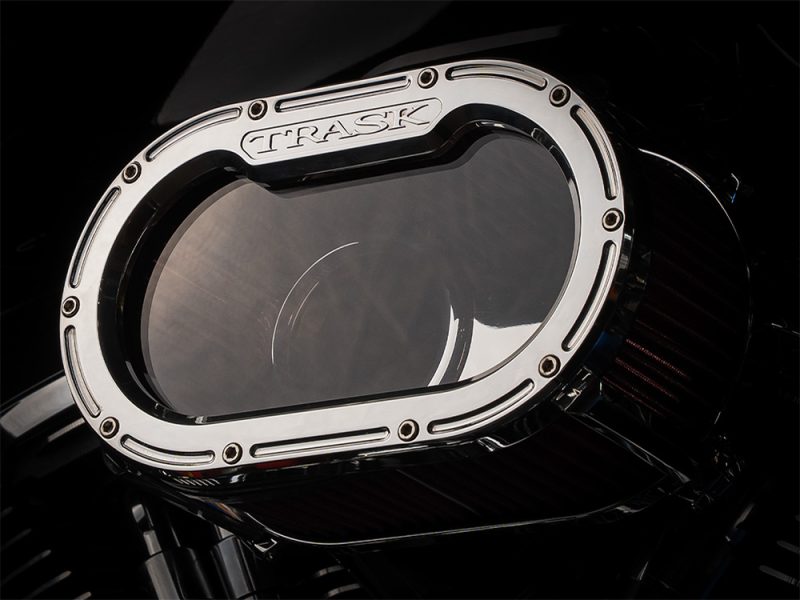 Polished motorcycle air cleaner cover with "TRASK" branding for custom Harley-Davidson bikes.
