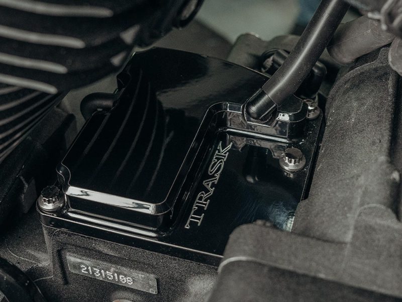 High-performance TRASK motorcycle engine component on a black engine block.