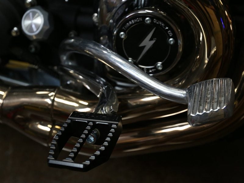 Close-up of motorcycle footpeg and chrome engine components at Revelry Motorcycles, highlighting custom parts and Chrome finish.