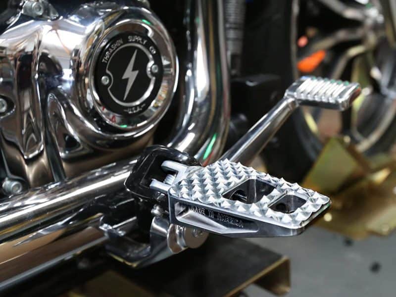 Polished motorcycle footpeg and chrome engine detail at Revelry Motorcycles, highlighting custom bike parts and accessories.