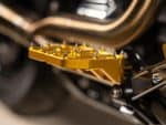 Close-up of gold motorcycle footpegs on a custom Revelry Motorcycles bike.