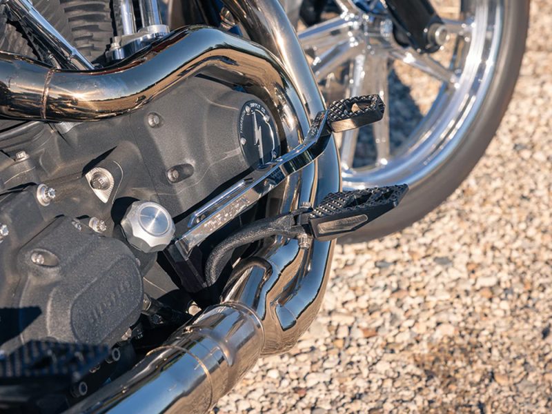 Shiny motorcycle engine with chrome exhaust pipes and textured foot pegs.