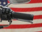 Handlebar grip and mirror close-up on a motorcycle with an American flag background.